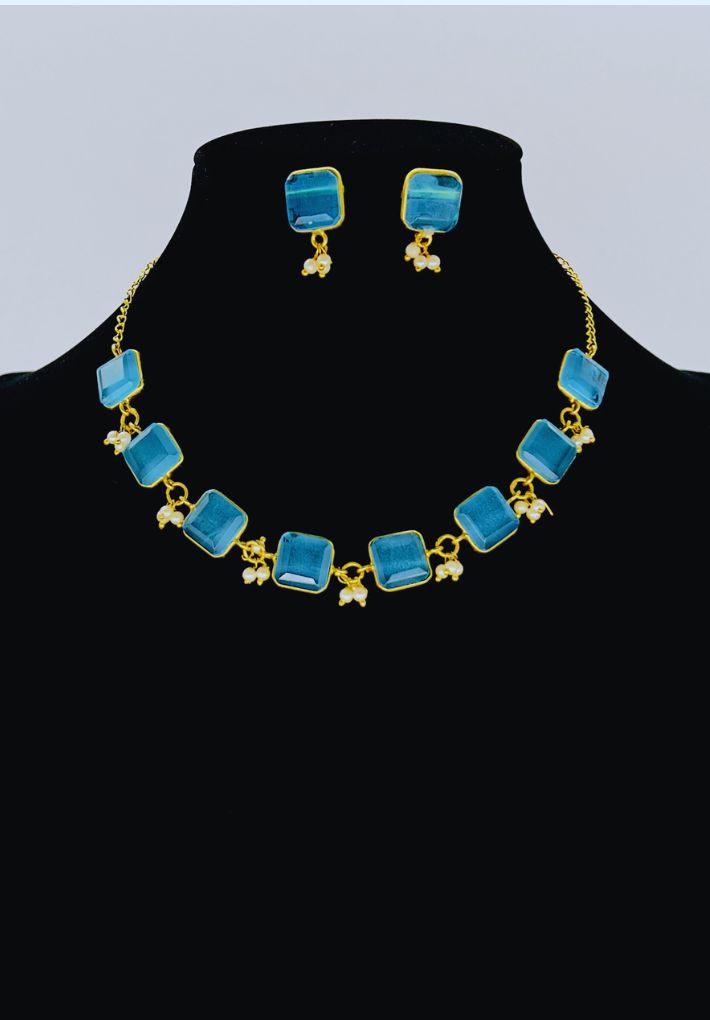Gold plated necklace and earring set featuring blue glass stones. Handcrafted statement jewellery.