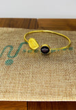 Gold plated adjustable handcuff with dark red stone. Handcrafted statement jewellery.