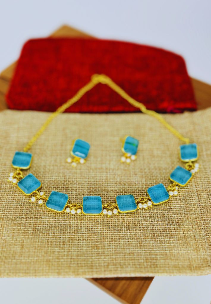 Gold plated necklace and earring set featuring blue glass stones. Handcrafted statement jewellery.