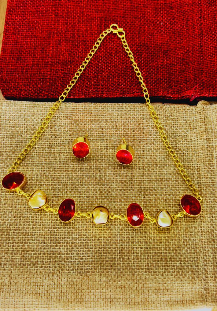 Gold plated necklace and earring set featuring red glass stones and raw pearl. Handcrafted statement jewellery.